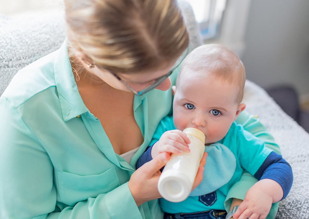 Bébé boit un biberon de lait maternel après un protocole de conservation en crèche