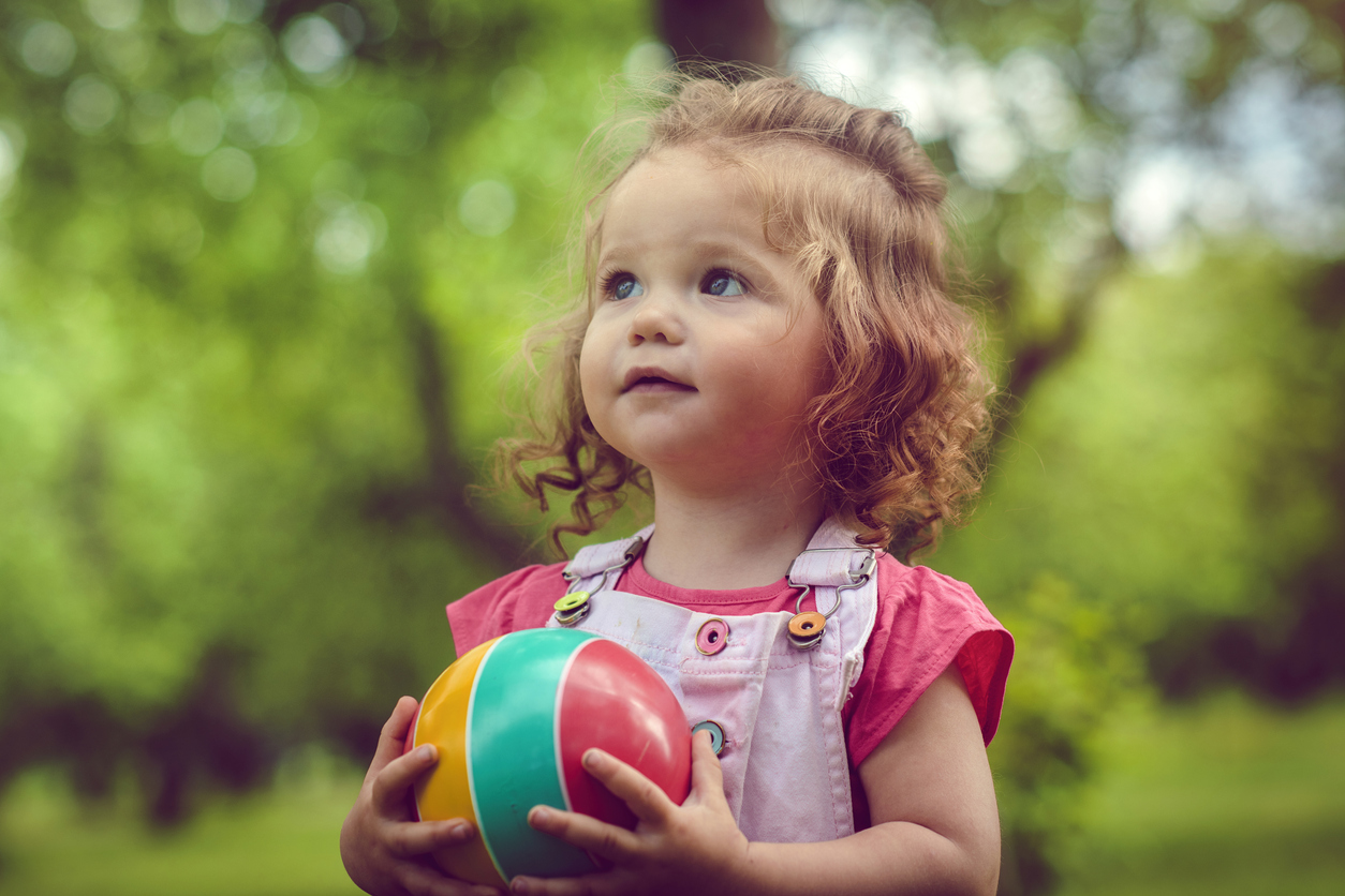 petite fille joue dehors avec un ballon