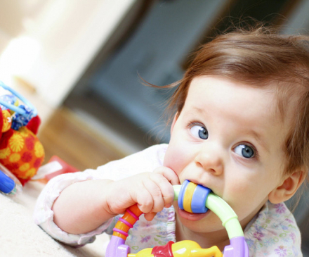 bébé avec jouet dans la bouche